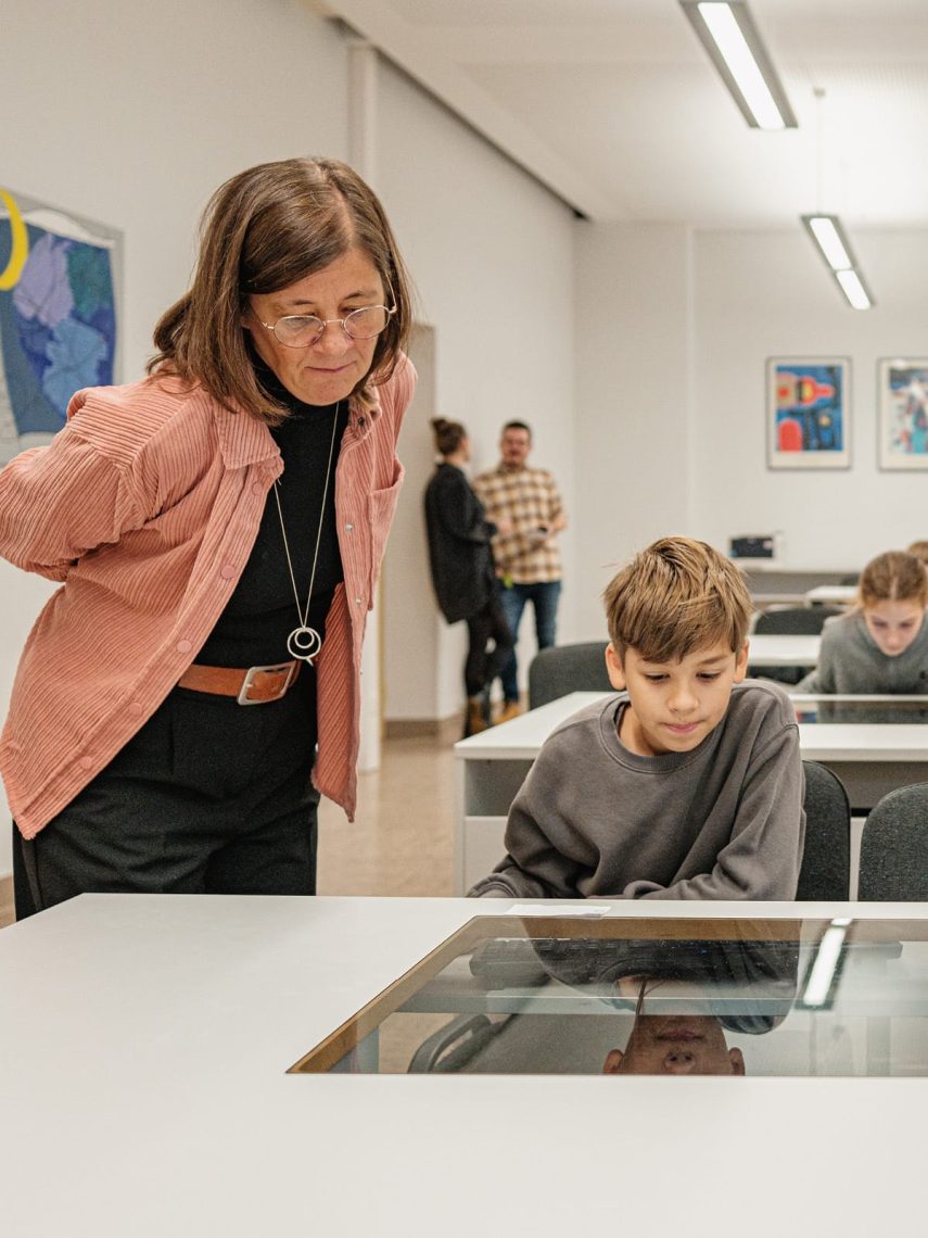 Lehrerin und ein Schüler schauen gemeinsam auf einem Bildschirm in der Marienschule Bielefeld